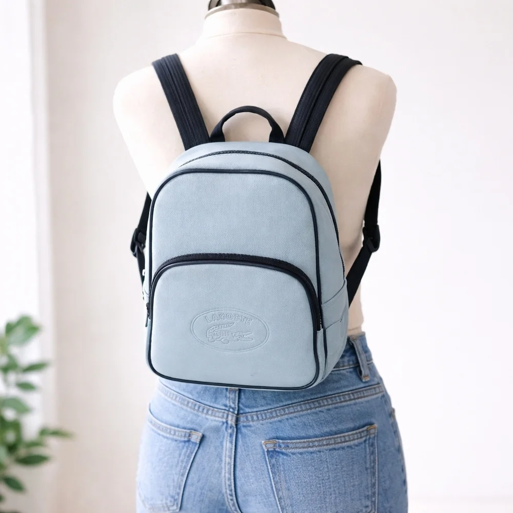 Lacoste mini backpack in a soft light blue shade with navy blue trim accents.